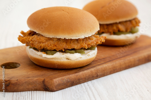 Homemade Burgers with fried chicken strips on a rustic wooden board on a white wooden background, low angle view. Close-up.