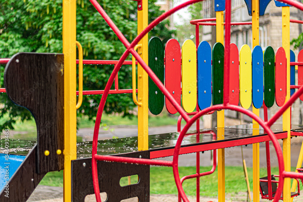 Empty swing at the playground in the rain. Children's swing in the park, wooden benches, slides, sports equipment. Empty city, quarantine. Empty swing at the playground in the rain. Children's swing in the park, wooden benches, slides, sports equipment. Empty city, quarantine.