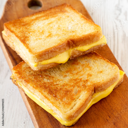 Homemade Grilled Cheese Sandwich on a rustic wooden board on a white wooden table, low angle view. Copy space.
