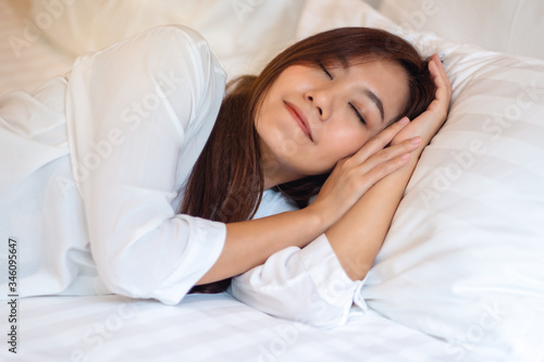 A beautiful asian woman sleeping in a white cozy bed at home