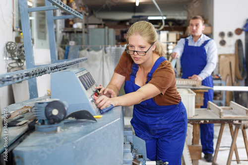 Female glazier working on glass bevelling machine