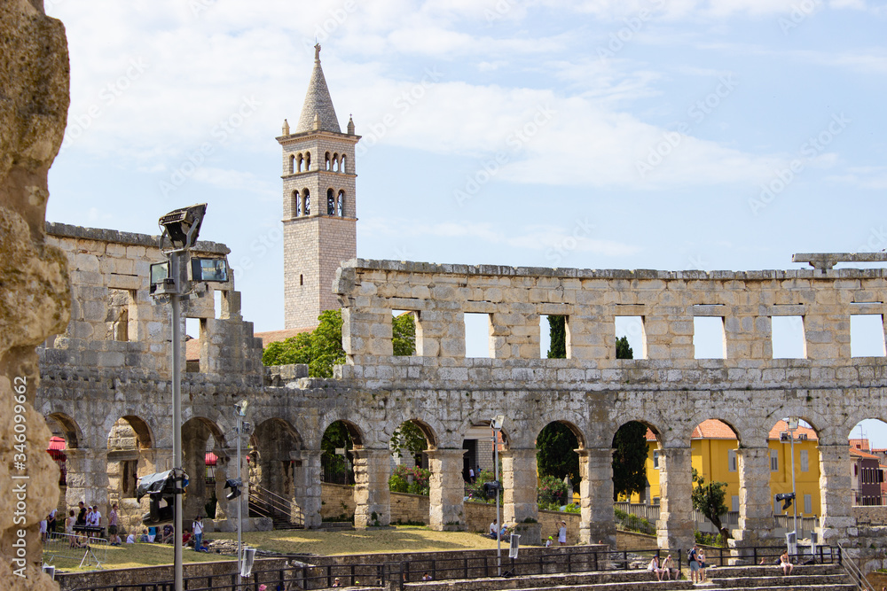 Fototapeta premium Interior of Pula Arena, the only remaining Roman amphitheatre entirely preserved, with the tower of the Church of St Anthony at the background, in Pula, Croatia