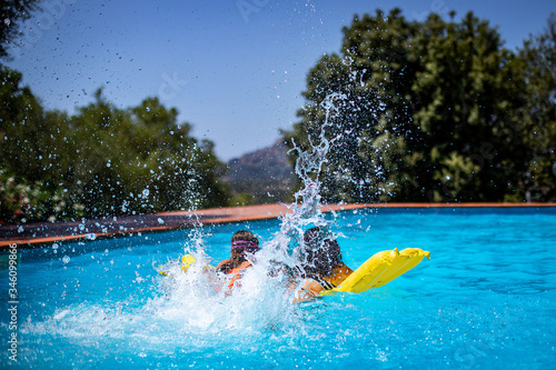 Two people splashing water with their legs at the swimming pool photo