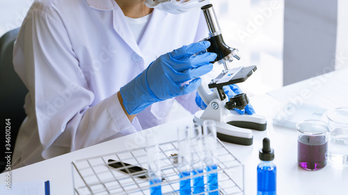Young Asian scientist Working looking through a  microscope doing research for analyzing a Experiments sample in a forensic laboratory.