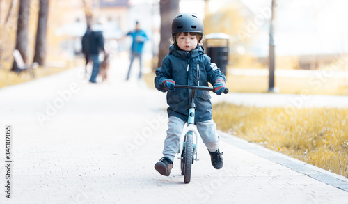 Little boy in a helmet - Learning to ride a first bike - Activity in the park - Shallow depth of field and sunlight.