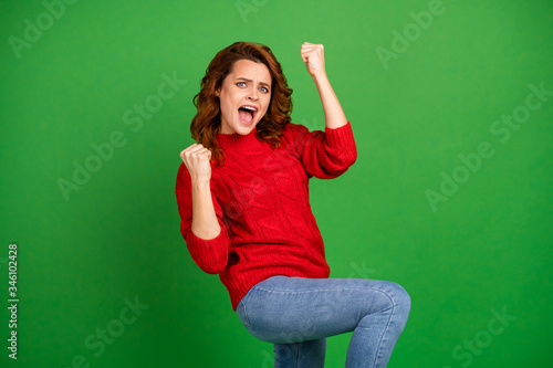 Portrait of excited cheerful delighted girl win competition raise fist scream yeah wear jumper isolated over vibrant color background