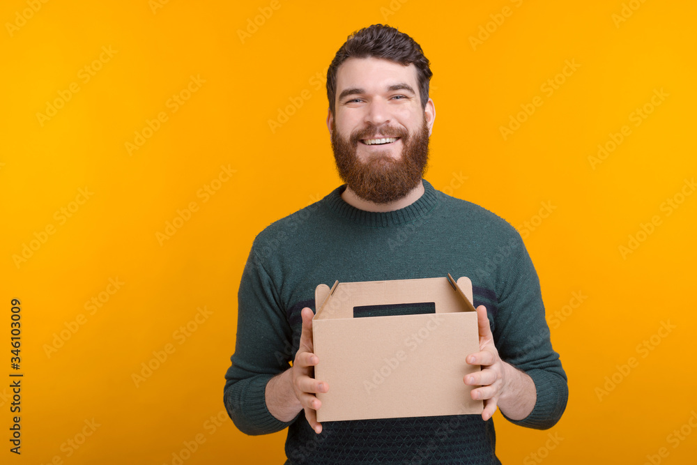 Hold your delivery box, a bearded man is handing it to you on yellow background. Hold your delivery box, a bearded man is handing it to you on yellow background.
