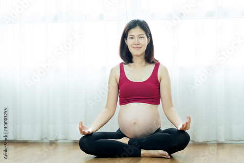 Beautiful asian pregnant woman sitting and doing yoga exercise at home