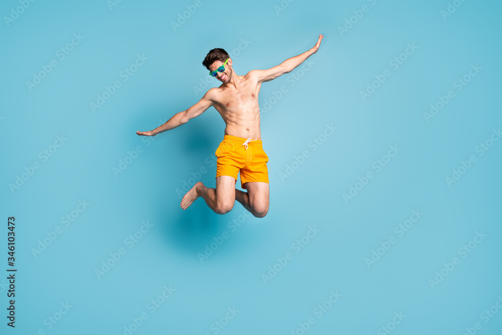 Full length body size view of his he nice attractive cheerful careless guy in swimming shorts jumping having fun time isolated on bright vivid shine vibrant green blue turquoise color background