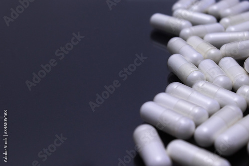 Tablou pe pânză Several white pills grouped on a black surface.