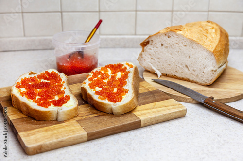 two large sandwiches with red caviar on a fresh french loaf photo