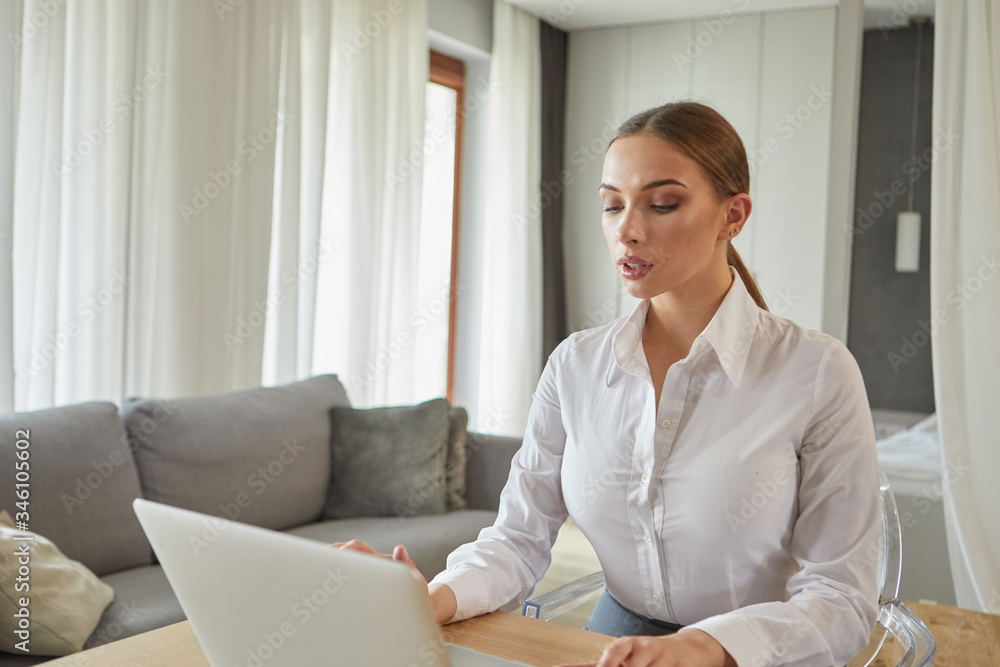 Concentrated young beautiful businesswoman working on laptop in home office. islolation, virus concept Concentrated young beautiful businesswoman working on laptop in home office. islolation, virus concept