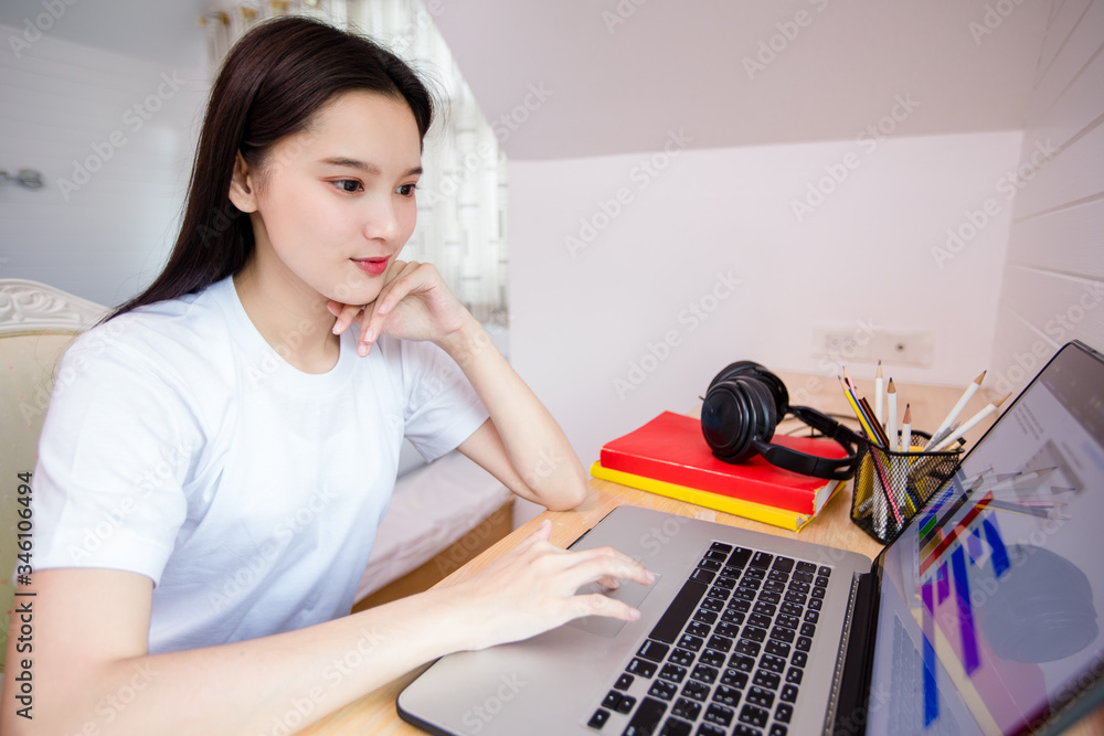 Asian woman happy cheerful cute beautiful is using a notebook computer and sitting on sofa for working from home. She is quarantined at home during the coronavirus epidemic. Asian woman happy cheerful cute beautiful is using a notebook computer and sitting on sofa for working from home. She is quarantined at home during the coronavirus epidemic.