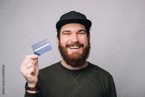 Close up portrait of a smiling bearded man showing a blue credit or debit card on white background. photo