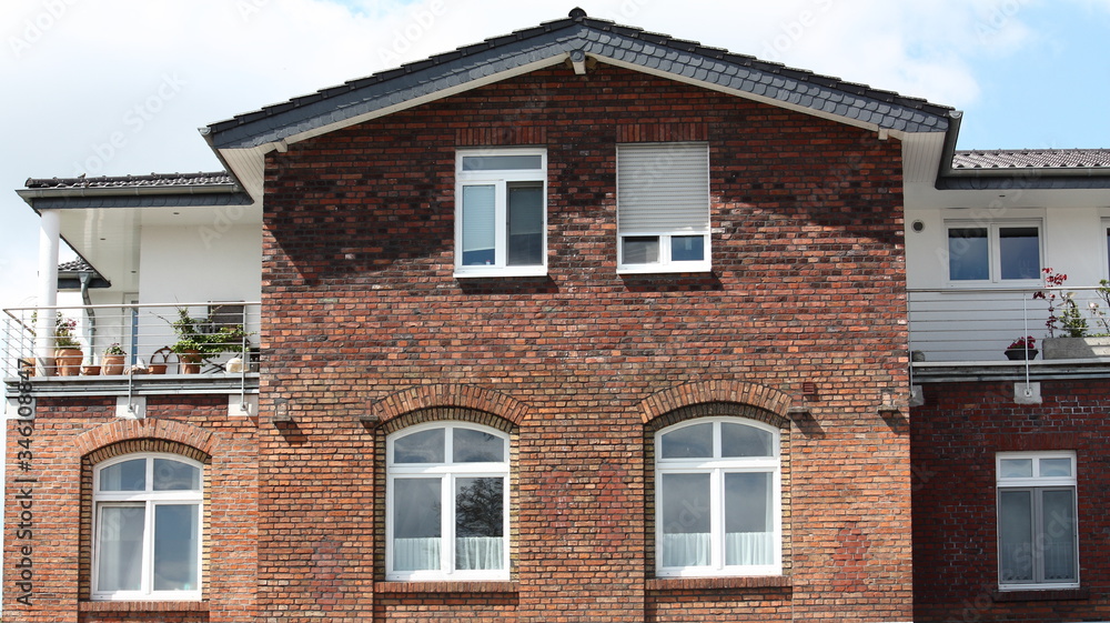 Backsteinfassade mit Fenstern und Dachterrasse