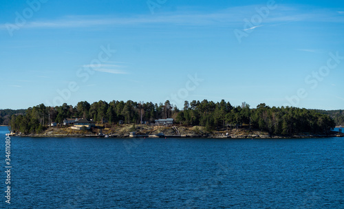 Picturesque summer houses painted in traditional falun red on dwellings island of the Stockholm archipelago in the Baltic Sea in the early morning. © fifg