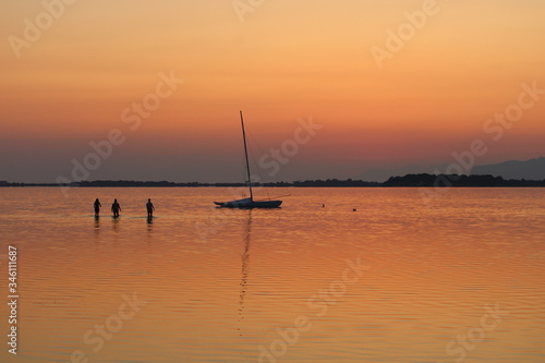 sailing boat moored on the sea at sunset and headland on the background