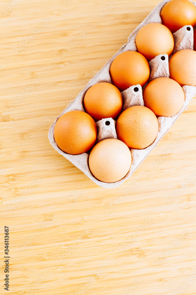 Overhead view of fresh brown chicken eggs in open egg carton box on wooden table background. Top view with copy space. Overhead view of fresh brown chicken eggs in open egg carton box on wooden table background. Top view with copy space.