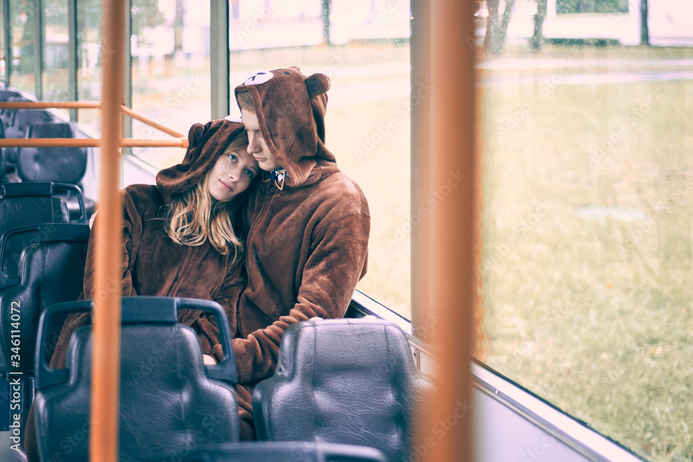 young couple in bear costumes. guy and girl in transport cuddle.