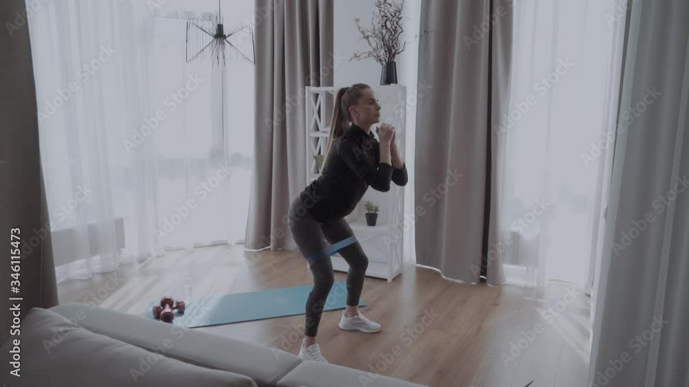 Young beautiful sporty athletic woman squats with fitness elves at home Young beautiful sporty athletic woman squats with fitness elves at home