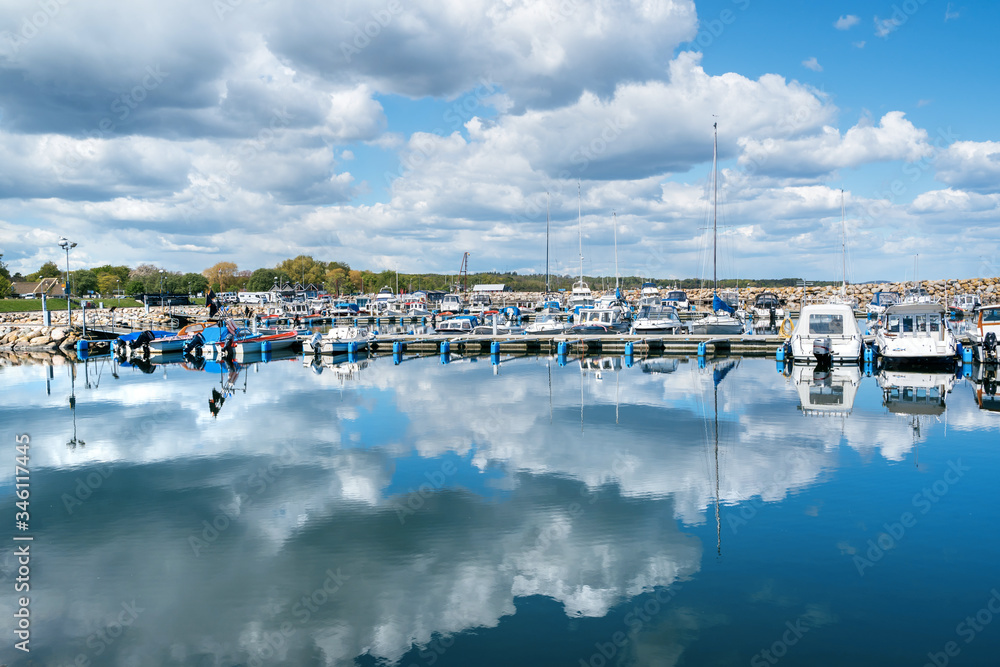Simrishamn, Sweden - May 13, 2019: Boats at the marina on sunny day with reflectiom on water