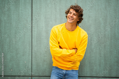 Photos male fashion model in yellow sweater laughing by green background