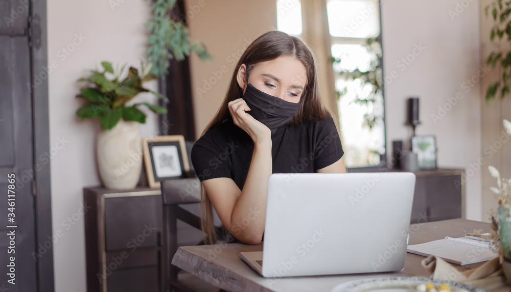 A girl in a medical black mask works at a computer and surf the internet. A girl in a medical black mask works at a computer and surf the internet.