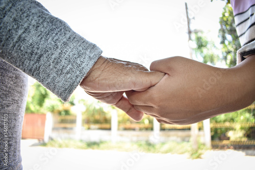 Hands of two people represent family warmth and care for the elderly.