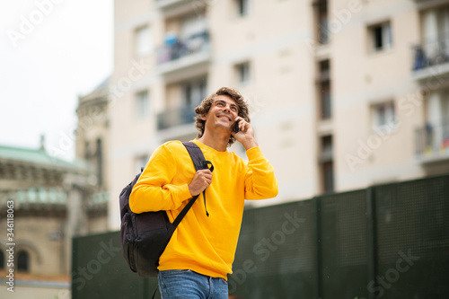 male student walking and talking with mobile phone