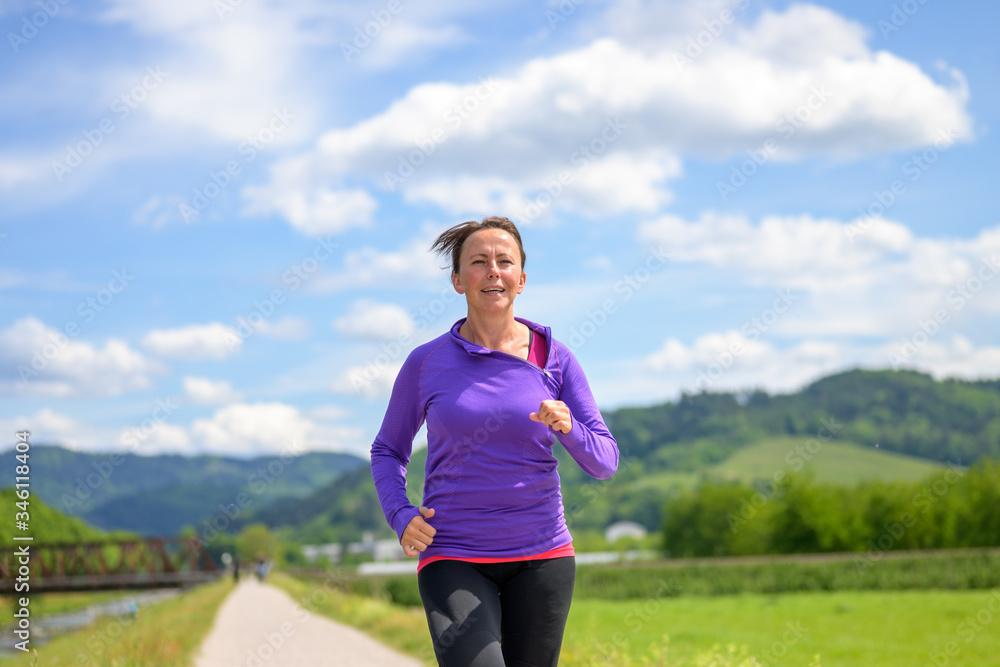 Fit active woman jogging in a spring landscape