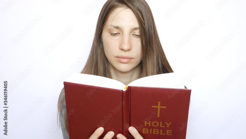A young beautiful woman reads the Holy Bible carefully A young beautiful woman reads the Holy Bible carefully