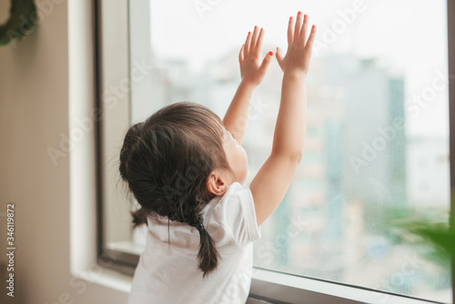 Foto A lovely kid girl sitting and looking outside trough the window