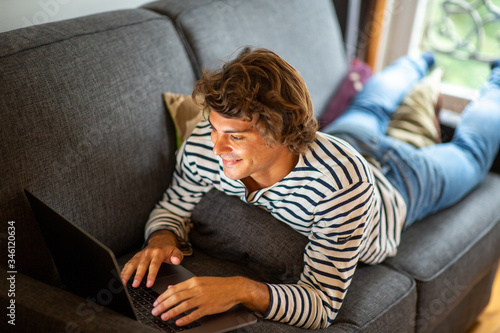 young man relaxing on couch at home using laptop computer