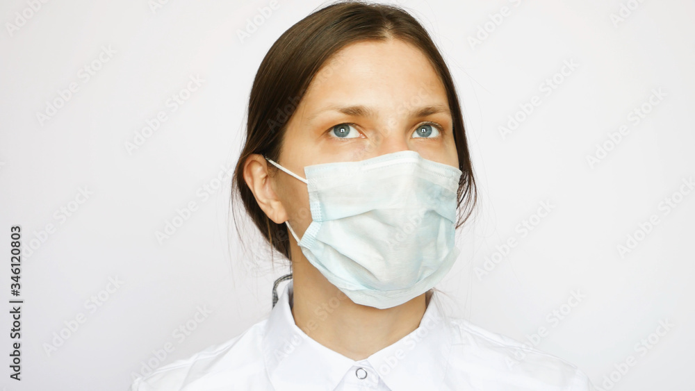 A portrait of pretty nurse with a protective mask looks into the distance