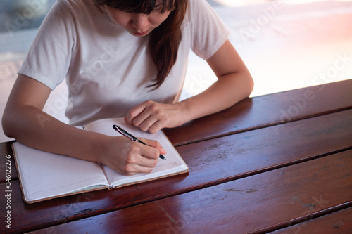 image of a woman writing on a blank notebook on the table. photo