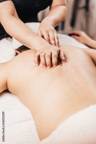 Hands of a masseuse on a female back during work - massage salon - spa treatments for female beauty and health