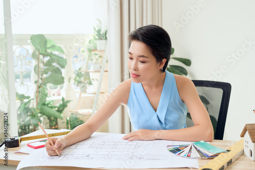 Asian Female architect working at home.She looking blueprints.