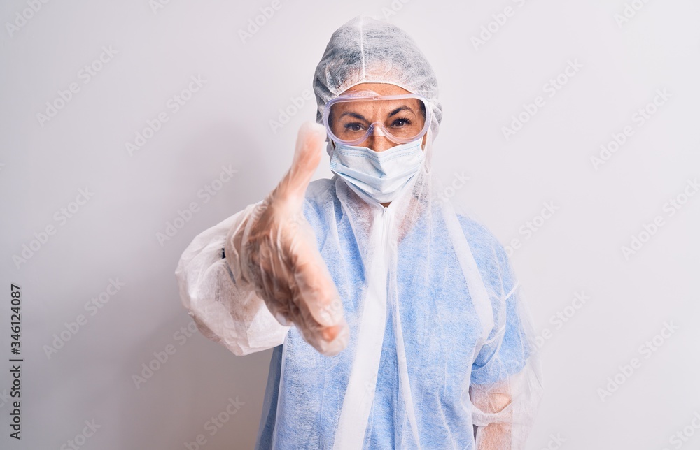 Middle age nurse woman wearing protection coronavirus equipment over white background smiling friendly offering handshake as greeting and welcoming. Successful business. Middle age nurse woman wearing protection coronavirus equipment over white background smiling friendly offering handshake as greeting and welcoming. Successful business.