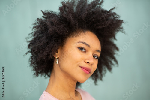 Close up beautiful young black woman with afro hair against green background