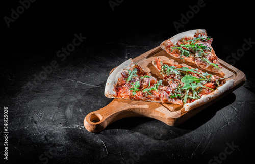 Slices of pizza with prosciutto and spices on a dark background. Pizza menu