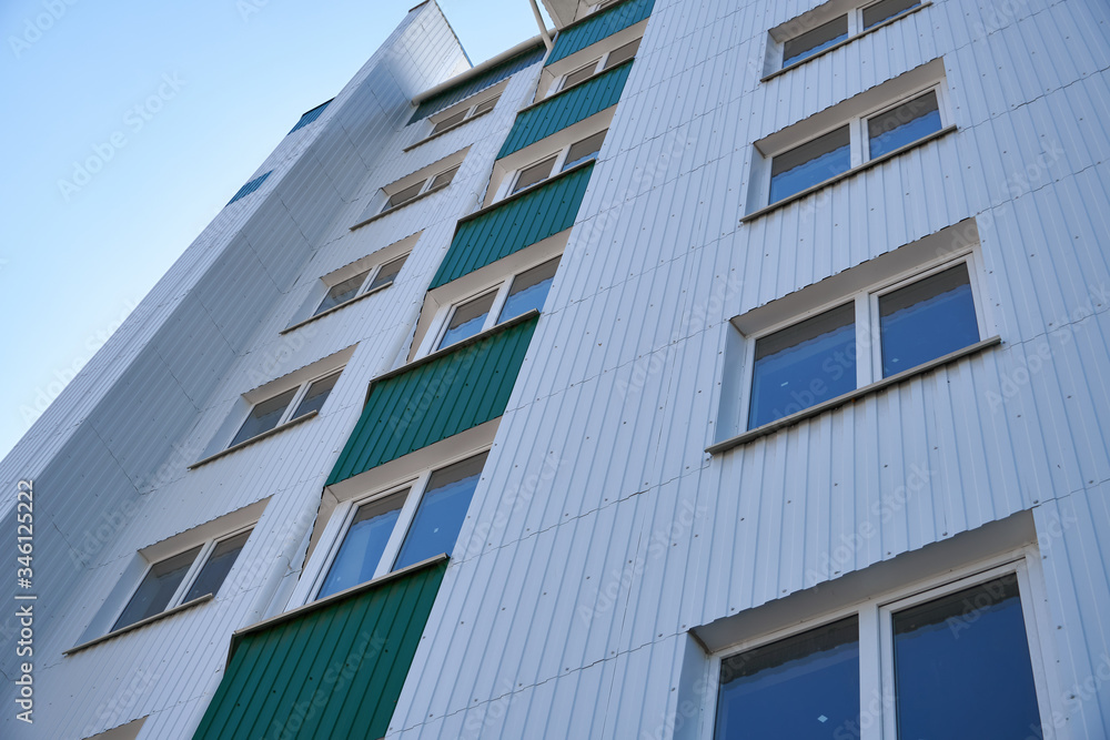 facade of a new multi-storey building with white and green metal siding, many Windows facade of a new multi-storey building with white and green metal siding, many Windows