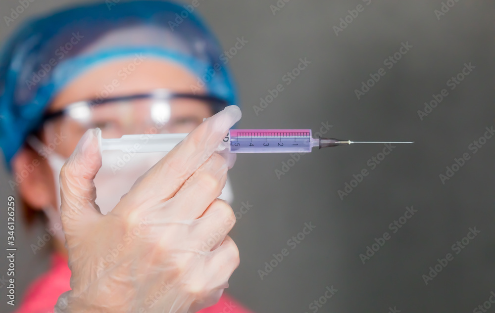 The nurse holds a syringe in her hand and prepares to give the patient an injection The nurse holds a syringe in her hand and prepares to give the patient an injection