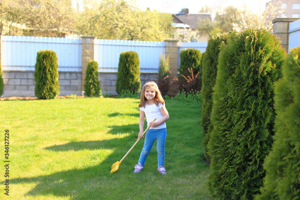 Little girl helps look after the lawn near the house