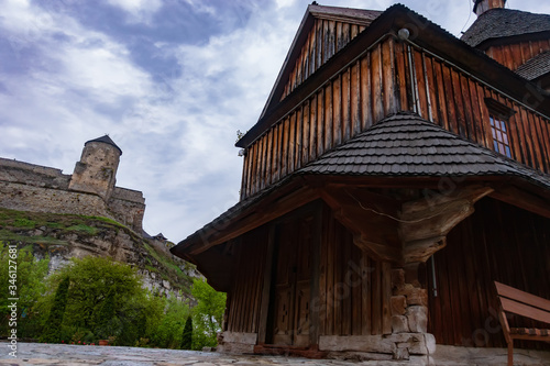 A wooden church at the bottom of the Smotrych Canyon. Holy Cross Church on the background of the fortress in Kamenetz-Podolsk photo