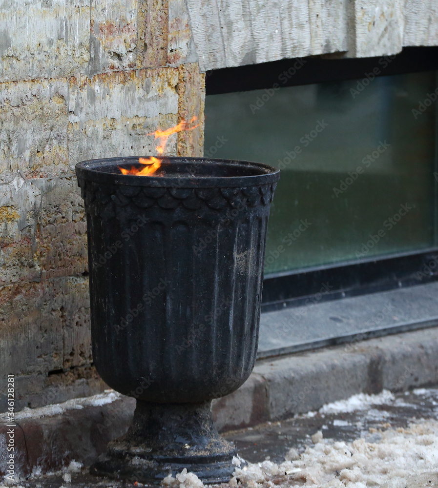 Obraz premium Street black metal urn with burning garbage