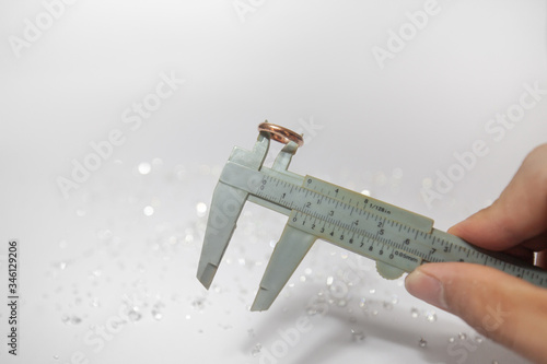 Tableau sur toile Hand holding a pinchbeck ring with vernier caliper