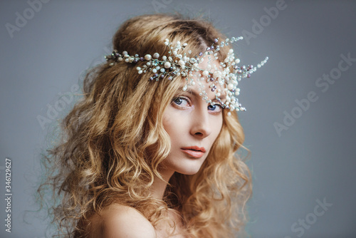 Young blue-eyed girl in with hair jewelry. Young woman with a hoop with stones and pearls. The concept of a wedding hairstyle and jewelry