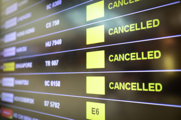 Flights cancelled and delayed on airport departure board due to covid-19 pandemic. Coronavirus causing disruption in air transport with airlines cancelling service. Travel and vacation cancellation