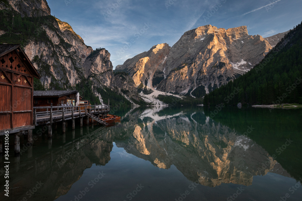 Boat house with boats at Lake Prags during sunset in the Dolomite Alps, refelction of the mountains on the water surface, South Tyrol Italy.