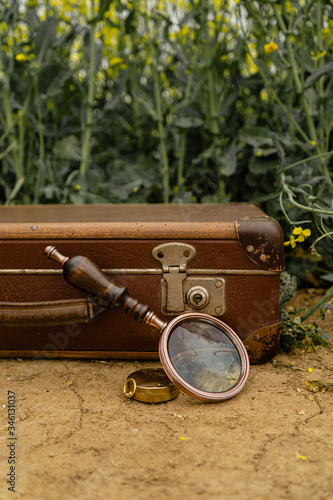 Old vintage brown suitcase with retro loupe and compass